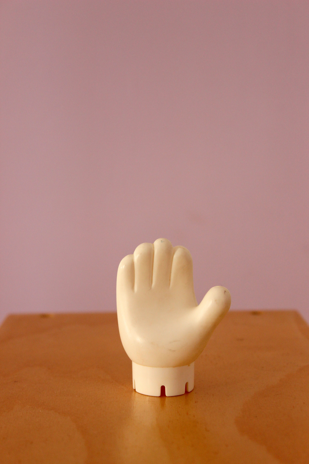 A small toy hand on top of a wooden table