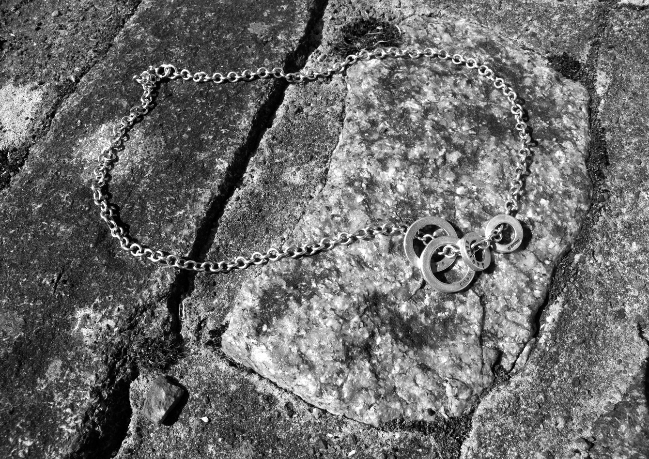 A black and white photo of a necklace on a rock